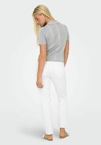 Top grigio a maglia con maniche corte, caratterizzato da un motivo testurizzato e applicazioni di perle sul colletto, abbinato a pantaloni bianchi a gamba dritta.