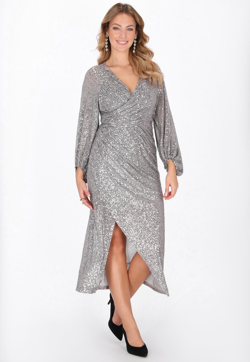 Hopeinen paljettimekko, jossa kietaisuominaisuus, pitkät puffhihat ja korkea halkio. Jokaisessa hihaosassa on rypytetty tekstuuri ranteen läheisyydessä.