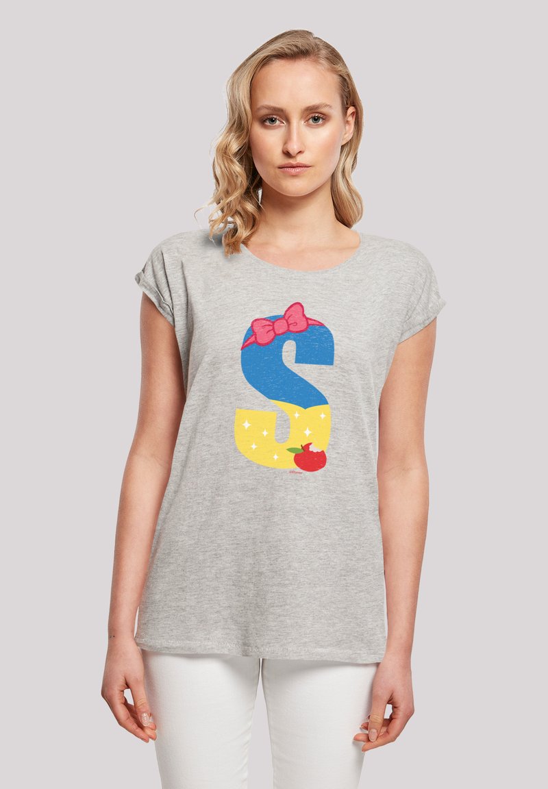 Camiseta corta gris de manga corta con un gran gráfico de la letra "S" en azul y amarillo, adornada con un lazo rosa y un acento de manzana roja. Textura suave.