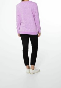Felpa lavanda con un motivo maculato, polsini e orlo a costine. Abbinata a pantaloni neri e sneakers bianche. Mostrata vista da dietro.