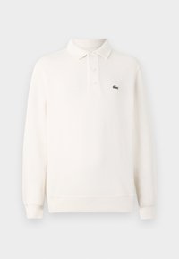 Polo blanc à manches longues avec trois boutons, poignets côtelés et petit logo crocodile vert sur la poitrine gauche.