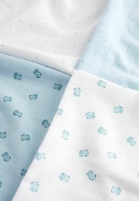 Cotton fabric featuring a light blue half with a teddy bear pattern and a white half with a grid and small blue stars. Soft texture.