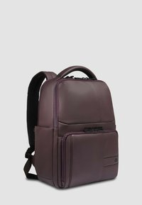 Zaino in pelle viola con schienale imbottito e spallacci regolabili. Presenta una tasca frontale con zip e una superficie liscia con dettagli di cucitura sottili.