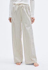 Pantalon ample et léger de couleur crème avec des rayures verticales foncées. Comprend une taille à cordon de serrage et une texture lisse.