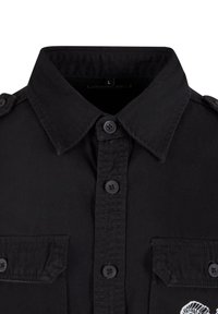 Black button-up shirt with a collar, two front pockets, and shoulder epaulettes. Smooth texture and fabric with a sewn design on the left pocket.
