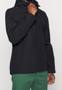 Černá voděodolná bunda se zipem vpředu, nastavitelnou kapucí a elastickými manžetami; má přední kapsy a hladkou, matnou texturu.