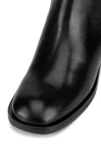 Czarny skórzany botek za kostkę o gładkiej fakturze, zaokrąglonym czubku i niskim, chunky obcasie. Posiada elastyczne boczne panele dla łatwego zakładania.