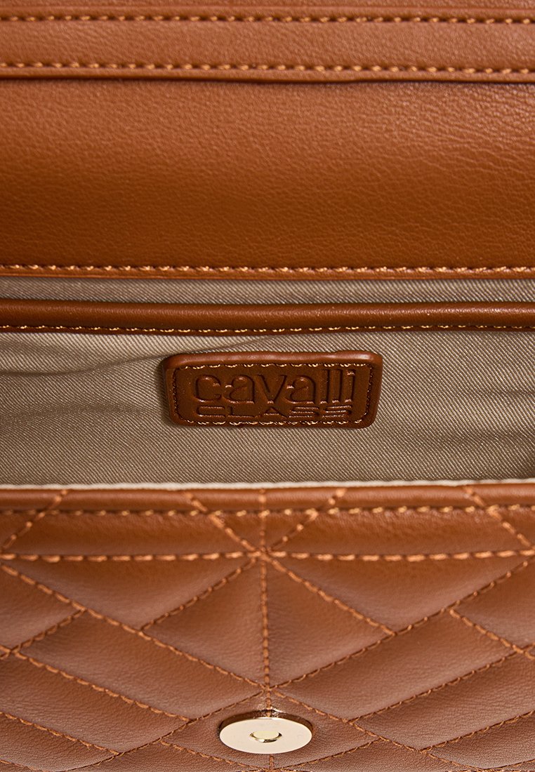 Intérieur d'un sac à main en cuir brun avec un motif matelassé, présentant une doublure beige et une étiquette de logo embossée. Détail en métal doré circulaire visible.