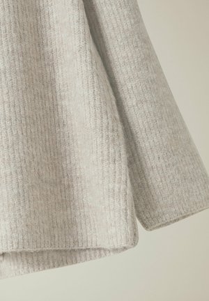 Lysgrå ribbet sweater, lavet af blød tekstureret stof, med en afslappet pasform og rundet underkant. Synlig detaljering i syningerne.