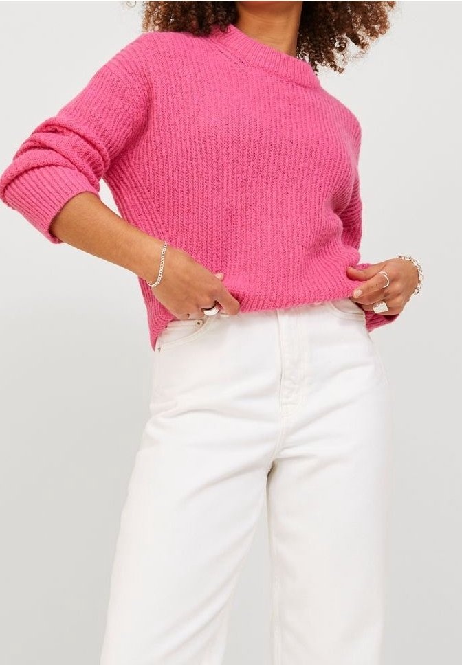Pull tricoté rose vif avec une texture côtelée et des manches courtes, associé à un jean blanc taille haute.
