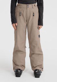 Beige ski pants with a relaxed fit, zippered pockets, and adjustable hem. Features a logo patch on the thigh and reinforced fabric.