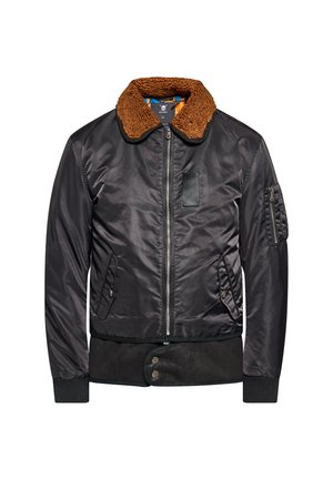 Schwarze Bomberjacke mit braunem Fleeckragen, Frontreißverschluss, zwei Seitentaschen, Reißverschlusstasche am Ärmel und Druckknopfabschluss am Saum.