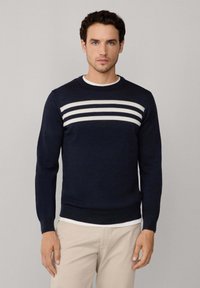 Maglione blu navy realizzato in tessuto a maglia, con strisce orizzontali bianche sul petto, scollo rotondo e design slim fit.