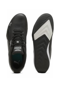 Czarne buty sportowe o smukłym designie, z perforowaną syntetyczną cholewką, fakturowaną podeszwą oraz kontrastowymi białymi i szarymi akcentami na spodzie.