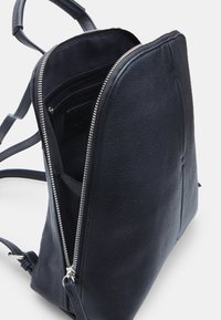Zaino in pelle nera con forma strutturata, chiusura con zip e scomparti interni, che mostra un esterno testurizzato e hardware argentato.