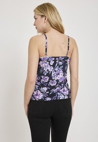 Kwiatowy top na ramiączkach w kolorze granatowym, z fioletowymi i białymi kwiatami. Regulowane cienkie ramiączka oraz dopasowany krój, gładka struktura tkaniny.