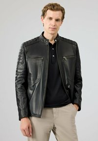 Zwarte leren jas met quilted schouders, ritszakken en een staande kraag. Gladde textuur met een aansluitend ontwerp.