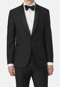 Zwarte tuxedo met satijnen revers, witte geplooide shirt en zwarte vlinderdas. Stof lijkt glad met een op maat gemaakte pasvorm. Klassiek formeel ontwerp.