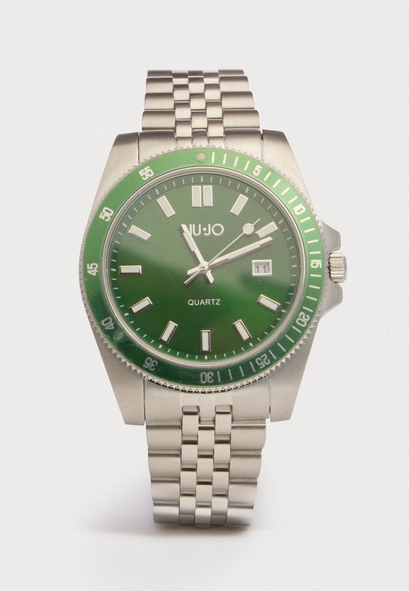Vihreä kvartsikello, jossa on ruostumattomasta teräksestä valmistettu ranneke, pyöreä kuori, heijastavat merkit ja päivämääränäyttö kello kolmessa. 60 minuutin bezel samansävyisessä vihreässä.