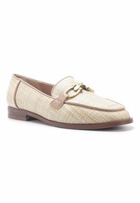 Mocasines tejidos en color beige con un upper de tela texturada, acentos en cuero marrón y un detalle de hardware en tono dorado en la parte superior. Tacón bajo.
