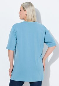 T-shirt azzurro chiaro di taglio relaxed-fit con maniche corte, scollatura rotonda e orlo dritto, realizzato in tessuto morbido con una trama liscia.