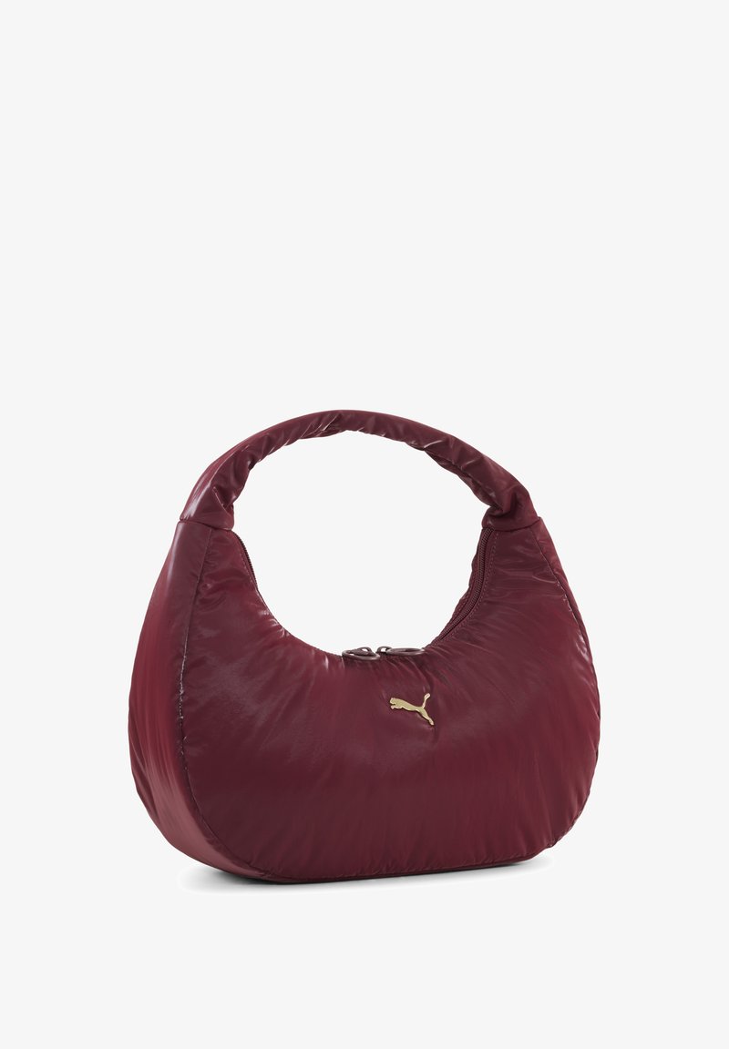Sac à main en nylon bourgogne avec une forme ronde, texture rembourrée et une seule poignée. Détail du logo doré accentue l'avant. Fermeture zippée.