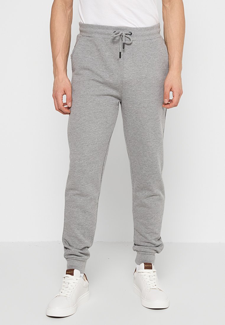 Pantalones deportivos grises de mezcla de algodón, con una cinturilla elástica y cordón ajustable, dobladillos con puño y bolsillos laterales.
