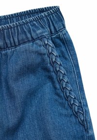 Denimske kratke hlače z elastičnim pasom, ki imajo pleteni poudarek na strani. Glavna barva je temno modra z mehkim, teksturiranim zaključkom.