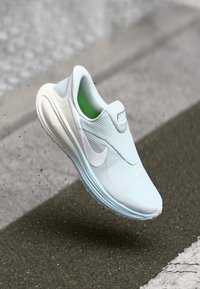 Αθλητικό παπούτσι σε ανοιχτό μπλε με υφασμάτινο επάνω μέρος με υφή, λευκό λογότυπο Nike swoosh και πράσινη εσωτερική επένδυση, με μαλακό, στρογγυλεμένο σχέδιο σόλας.