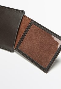 Inderside af sort læderpung med en brun ruskindslignende sektion med et klart ID-vindue, syninger langs kanterne og en glat tekstur.