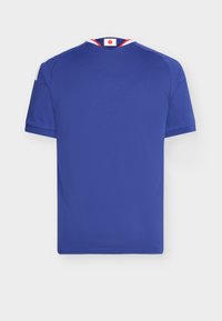 Blå atletisk tröja av lätt tyg. Har korta ärmar, rund halsringning och en röd och vit detalj vid kragen.