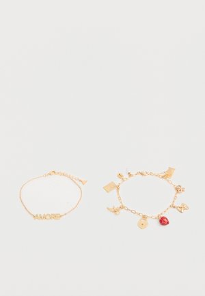 Twee gouden armbanden met schakels op een witte achtergrond; één met de tekst "AMORE", de andere met meerdere bedels waaronder een rode aardbei en een gouden slot.