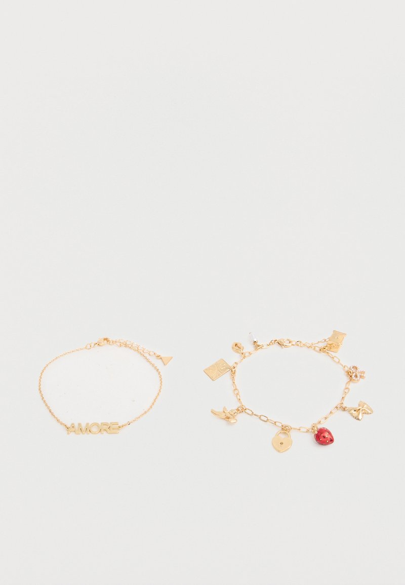 Deux bracelets chaîne en or sur fond blanc ; l'un avec le texte "AMORE", l'autre avec plusieurs breloques dont une fraise rouge et un cadenas en or.