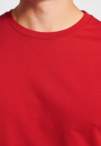 Rotes Baumwoll-T-Shirt mit rundem Halsausschnitt und kurzen Ärmeln. Der Stoff ist glatt mit einem leichten Stretch und vermittelt ein lässiges Design.