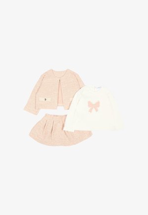 Giacca in tweed rosa e gonna abbinata posate accanto a una maglietta bianca a maniche lunghe con un fiocco rosa sul davanti.