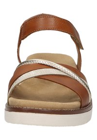Braune Ledersandale mit breitem Riemen und silbernem Akzent. Texturiertes Fußbett und eine weiße Sohle. Offenes Rückendesign für einfaches Anziehen.