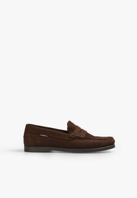 Mocasines marrones de ante con suela plana, que cuentan con una correa decorativa y costuras en la puntera. Logo en el lateral.