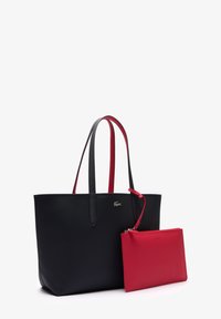 Bolso tote de cuero negro con asas rojas y un pequeño estuche con cremallera a juego, con acabado texturizado y detalle de logo dorado.