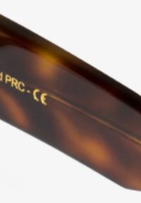 Occhiali da sole con motivo tartaruga e finitura lucida. Presentano testo dorato sulla braccio. Forma curvata, design leggero e texture liscia.