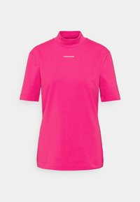 Fuchsia T-shirt met korte mouwen van katoen, met een hoge hals en een witte "CALVIN KLEIN JEANS" logo op de borst. Gladde textuur en aansluitend ontwerp.