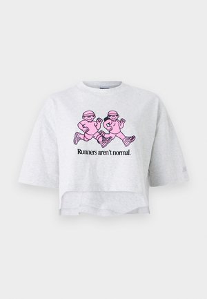 T-shirt cropped gris en coton avec des manches courtes. Affiche un graphique rose de deux silhouettes en train de courir et le texte "Les coureurs ne sont pas normaux."