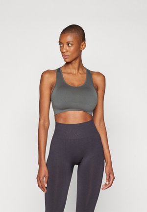 Soutien-gorge de sport gris avec un décolleté en scoop et des bretelles épaisses, associé à des leggings noirs taille haute. Texture lisse, design minimaliste et forme ajustée.