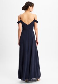 Navy avondjurk met off-shoulder mouwen, gerimpelde lijfje en een vloeiende rok. Bevat een V-achterkant en ritssluiting. Zacht, lichtgewicht stof.