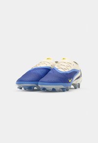 Blue and white soccer cleats with textured upper, yellow accents, and transparent sole. Features a streamlined design and rounded toe.