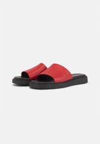 Røde skinnesandaler med åpen tå, svart gummisåle, og et minimalistisk design med en glatt tekstur uten synlig maskinvare.