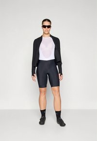 Casaco de ciclismo leve preto, body branco, calções pretos e sapatos desportivos. Óculos de sol completam o outfit atlético. Texturas lisas e ajustadas.