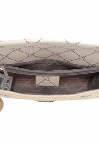 Interno di borsa beige con texture e tasca con zip. L'interno presenta una fodera decorata con forme a diamante e accenti circolari.