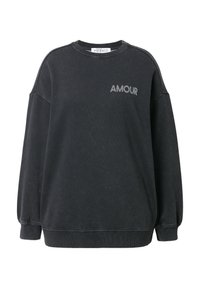 Svart sweatshirt av mjukt tyg, med en lös passform, långa ärmar, ribbade manschetter, och ordet "AMOUR" tryckt i grått på framsidan.