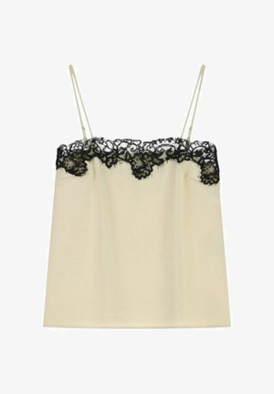 Top in cotone beige con spalline sottili, caratterizzato da un bordo in pizzo nero lungo il scollatura e l'orlo superiore. Tessuto morbido e liscio senza decorazioni visibili.