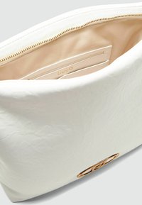Witte faux lederen tas interieur, met een beige voering, een ritssluiting en een geperst logo; gladde textuur en ronde vorm.
